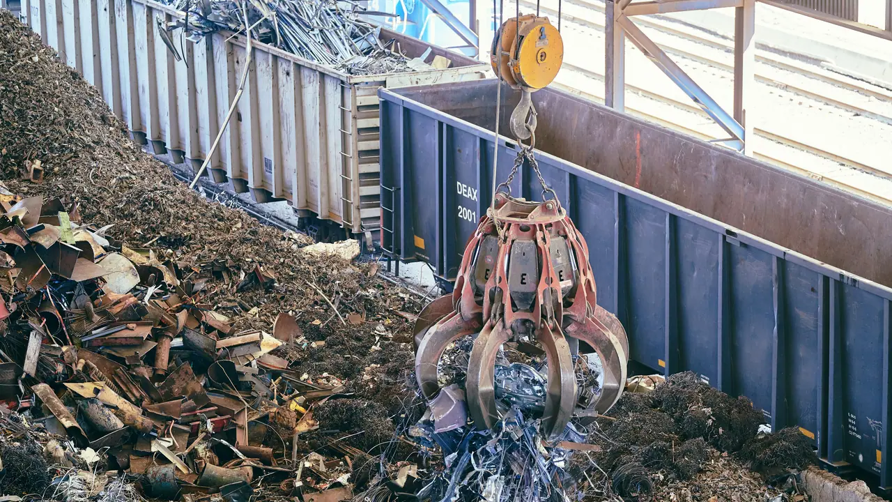 Grab crane lifting shredded scrap metal at a recycling yard