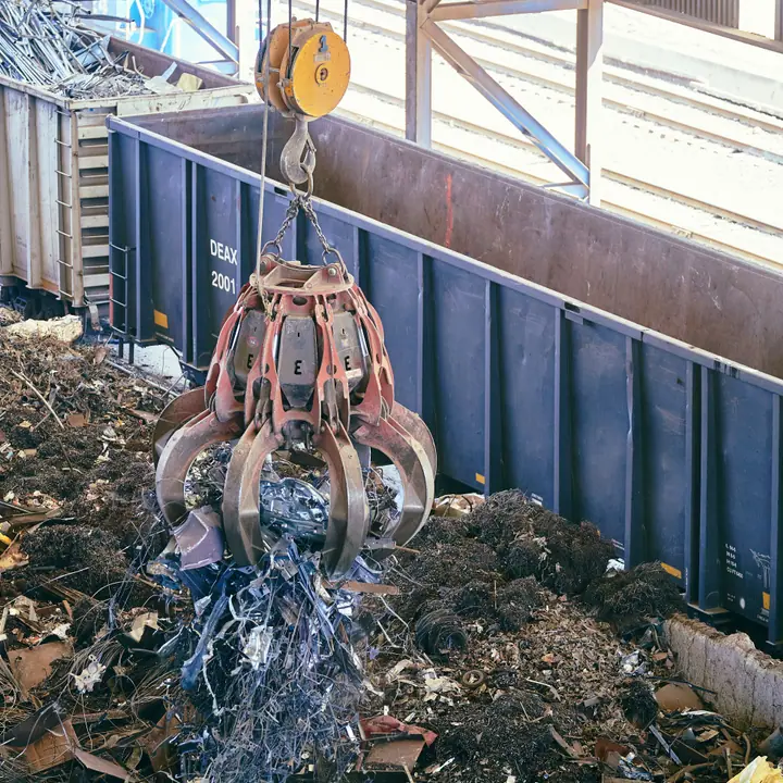 Grab crane lifting shredded scrap metal at a recycling yard